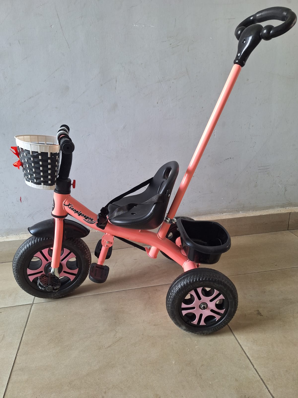 Kids tricycle with parent push handle, front basket and rear storage tray available in pink and blue for children aged 2 to 5 years.