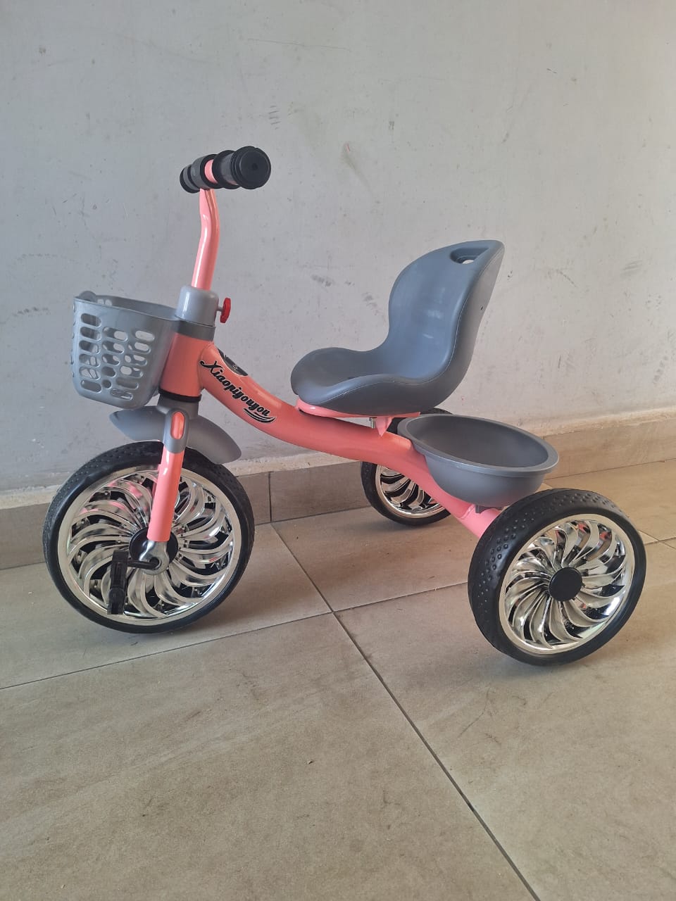 Baby tricycle with front basket, rear storage tray, ergonomic backrest seat, available in pink and blue.